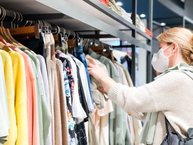  Giysi mağazasında koruyucu maskeli bir kadın..