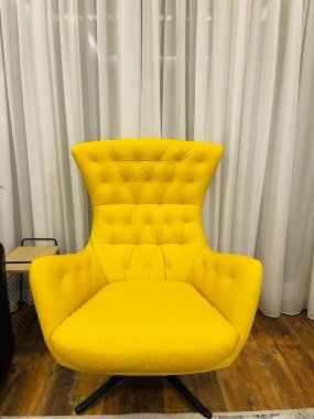 Sarı deri koltuk. Beyaz perdelerin arkasındaki oda..