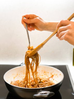 Kadın ellerini kapayın ve deniz ürünleriyle makarna pişirin. Yüzü yok. 