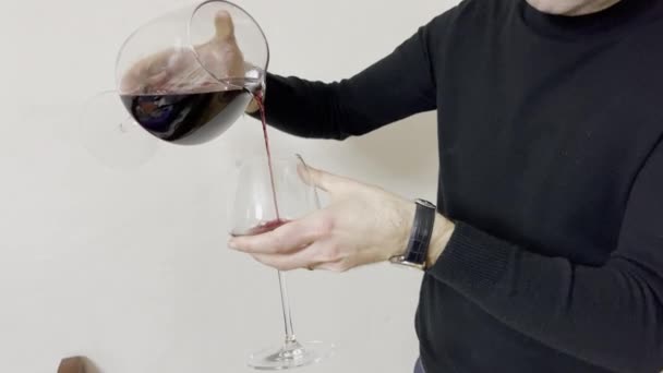 Uomo che indossa il golf nero versando vino rosso in un bicchiere. — Video Stock