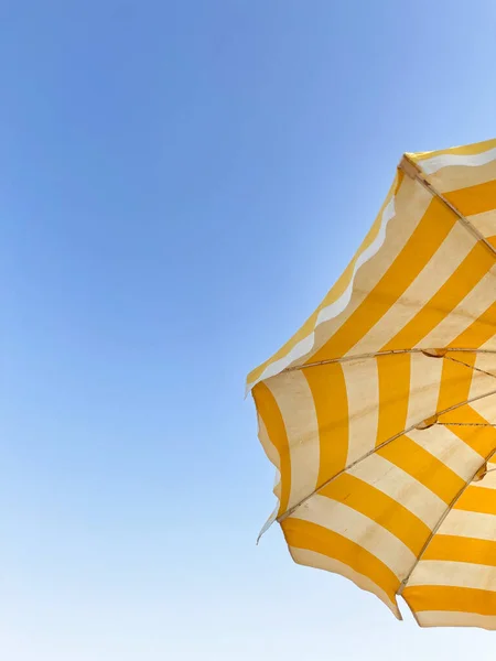 Açık mavi gökyüzünde sarı şemsiye. Yaz tatili konsepti. Telifsiz Stok Imajlar