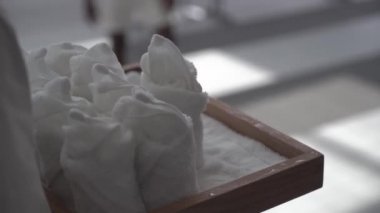 Genç bir adam otelin lobisinde yürür ve beyaz ıslak bir havlu alır.