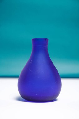 Koyu yeşil ve beyaz arkaplanda mavi eğimli vazo