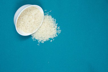 Beyaz seramik kasede uzun tahıllı beyaz pirinç, arka planda bir renk. Boşluğu kopyala