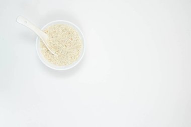 Beyaz bir seramik kase ve kaşık ve beyaz arka planda izole edilmiş uzun tahıllı beyaz pirinç. Boşluğu kopyala