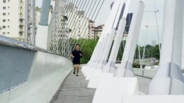 PUTRAJAYA, Malezya - 10 Ekim 2020: Covid-19 tüm dünyayı vurmadan önce genç bir adam halka açık alanlarda özgürce koştu. Kalp atışlarını izlemek için kırmızı akıllı bir saat takıyordu.