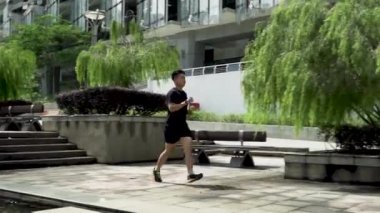 PUTRAJAYA, Malezya - 10 Ekim 2020: Covid-19 tüm dünyayı vurmadan önce genç bir adam halka açık alanlarda özgürce koştu. Kalp atışlarını izlemek için kırmızı akıllı bir saat takıyordu.