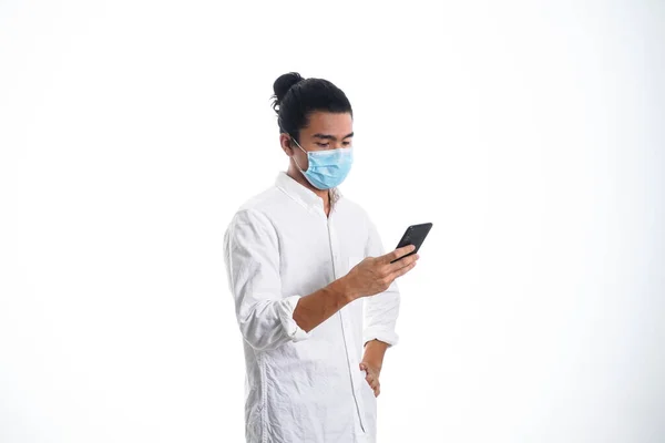 Covid19 医疗保健和医药的概念 一个拿着面具在电话里看新闻的年轻人 支持社交距离 — 图库照片