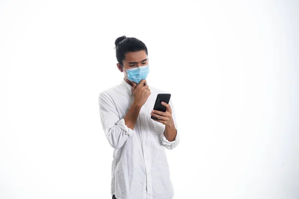 Covid19 医療や医療の概念 顔のマスクをした若い男が電話でニュースを読んで社会的距離を支えている — ストック写真