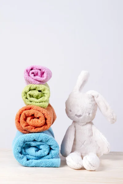 Полотенца сложены булочки. Мягкий игрушечный кролик — стоковое фото
