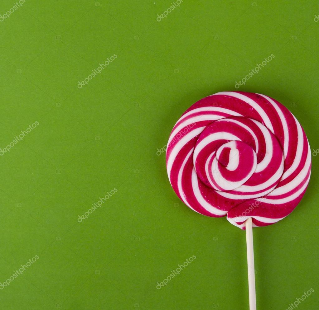 RED lollipop on green background with copy space Stock Photo by