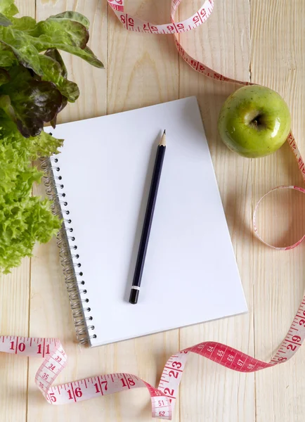 Empty notebook with vegetable salad and apple — Stock Photo, Image