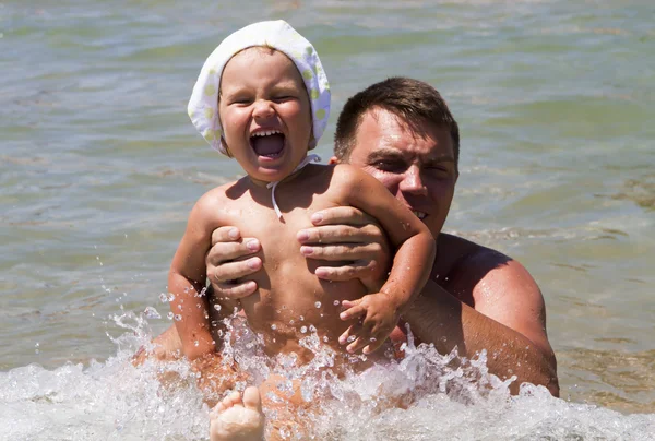Мужчина отец и дочь маленькая девочка плавает в море в волнах — стоковое фото