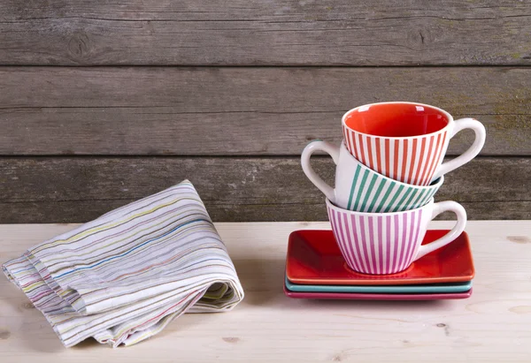 Copos de café listrados coloridos na prateleira e toalha de algodão — Fotografia de Stock