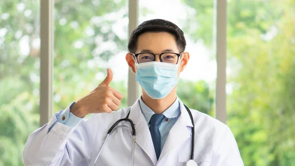 若いアジアの医師は オンラインポッドキャストを介してCovid 19やコロナウイルス感染を防ぐためにマスクを正しく着用する方法を示しています — ストック写真