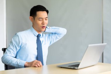 Genç Asyalı iş adamı bilgisayarla uzun süre çalıştıktan sonra boyun ağrısı çekiyor. ofis sendromu kavramı