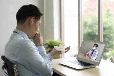Genç işadamının ofisinde boğaz ağrısı ve hemofili var. Bu yüzden Asyalı doktora danışmak için video konferansına gidiyor. teletıp kavramı