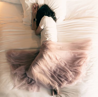 Yatağa uzanmış pembe etekli güzel bir kadın.