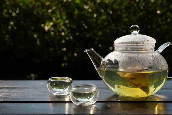 picture of people pouring hot water into clear glass kettle to make tea in afternoon in garden