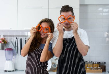 Genç, beyaz bir çift ellerinde meyve, mutfakta durmuş kahvaltı hazırlıyorlar. aile kavramı