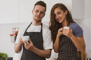 Genç beyaz bir çift, birlikte sağlıklı bir kahvaltı etmeden önce mutfakta kahve içiyor.