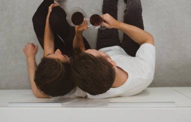 Genç, beyaz bir çiftin yıl dönümünde mutfakta oturup şarap içerken çekilmiş otantik bir fotoğrafı.