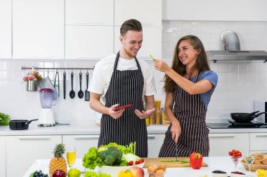 Kocası mutfakta kahvaltıda sağlıklı salata pişirmek için tablet okurken, beyaz kadın sebze doğruyor. çift kavramı