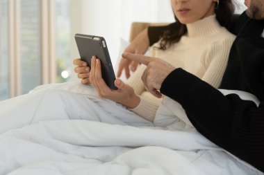 Kafkasyalı çift yatakta oturup yatak odasındaki tabletten film izliyor. birliktelik konsepti