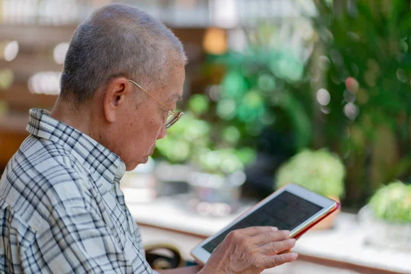 Sênior Asiático Homem Usando Tablet Para Jogar Social Media Casa — Fotografia de Stock