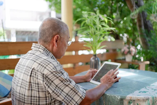Sênior Asiático Homem Usando Tablet Para Jogar Social Media Casa — Fotografia de Stock