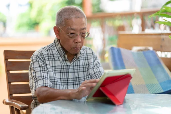 Sênior Asiático Homem Usando Tablet Para Jogar Social Media Casa — Fotografia de Stock