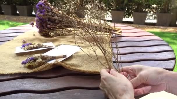Крупным Планом Видны Руки Пожилой Пенсионерки Занимающейся Укладкой Сухих Цветов — стоковое видео