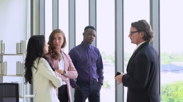 高级经理站在窗边 鼓励年轻的商业团队 包括高加索人和黑人 在办公室里创建新的项目 多样性概念 — 图库视频影像