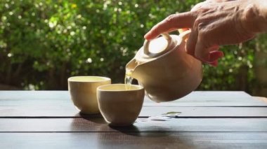 Bahçedeki masaya Earl Grey çayı döken yaşlı insanların gerçek zamanlı görüntüleri.