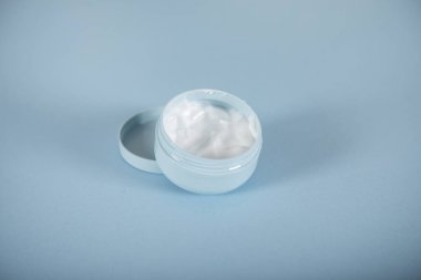 Masanın arkasında yüz kremi var.