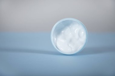 Masanın arkasında yüz kremi var.