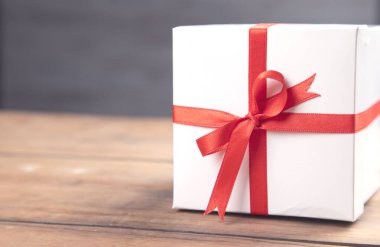 Tahta masanın üzerindeki beyaz hediye kutusu.