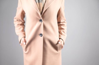  Gri arka planda, cep ceketli bir kadın.