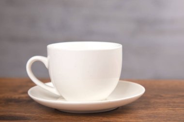 Ahşap masanın arkasında bir fincan kahve.