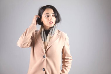 Gri arka planda ceketli genç bir kadın.