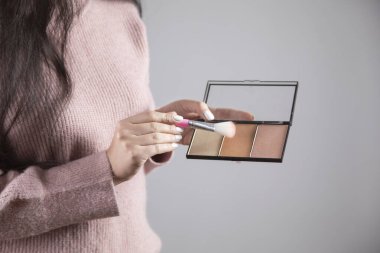 Elinde fırça ve fosforlu kalem tutan genç kadın.