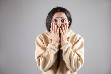 Gri duvar arkasında korkmuş genç bir kadın.