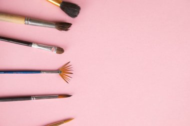 Pembe masa arkaplanındaki boya fırçaları