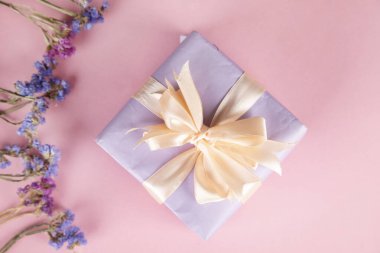 Pembe arka planda renk çiçekleri olan hediye kutusu