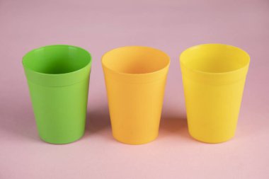 Pembe masa arkasında renkli plastik bardaklar