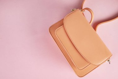 Pembe masa arkasındaki turuncu çanta.