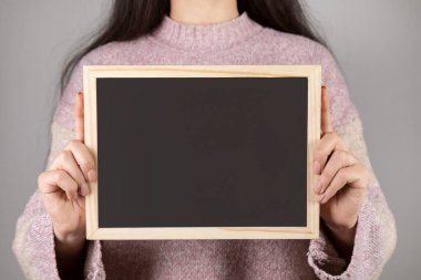 Gri duvar arkasında tahtası olan kadın.