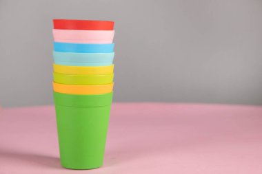 Pembe masa arkasında renkli plastik bardaklar