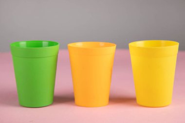 Pembe masa arkasında renkli plastik bardaklar
