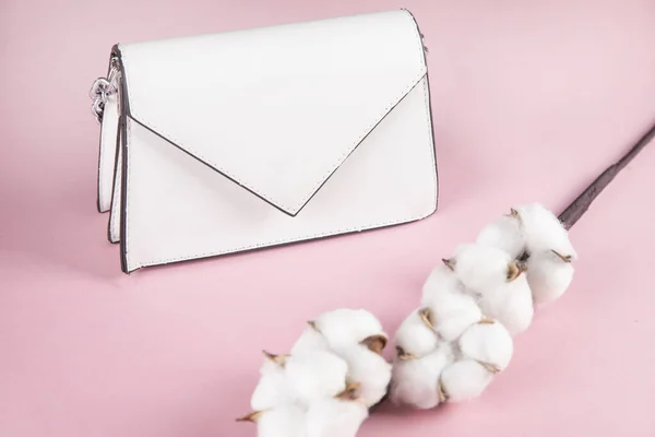 white bag and cotton branch on pink background